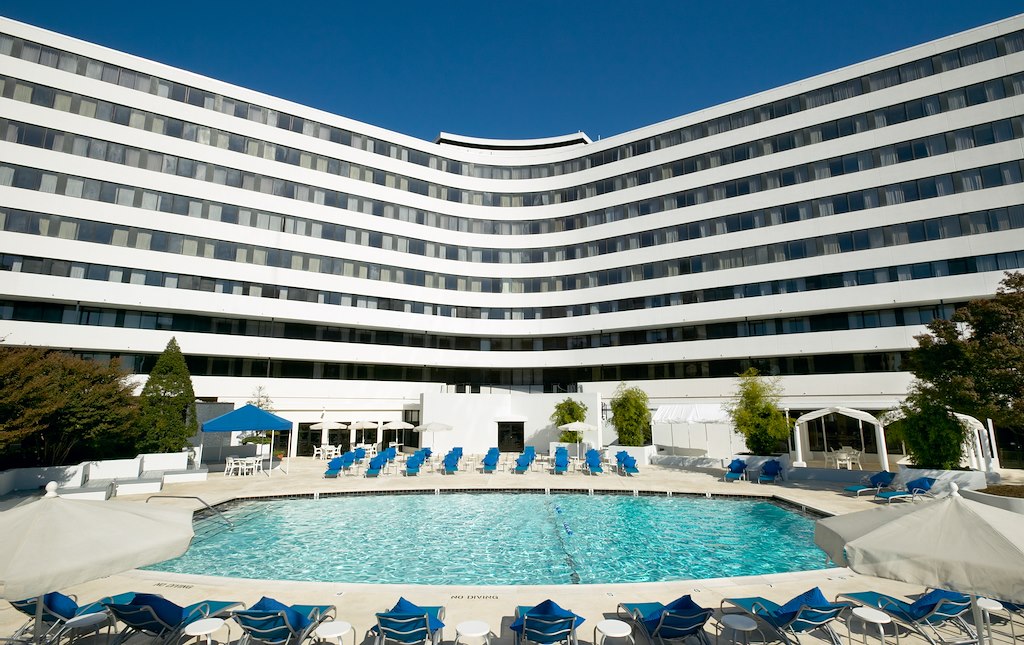 A large white building with a pool area in front of it.