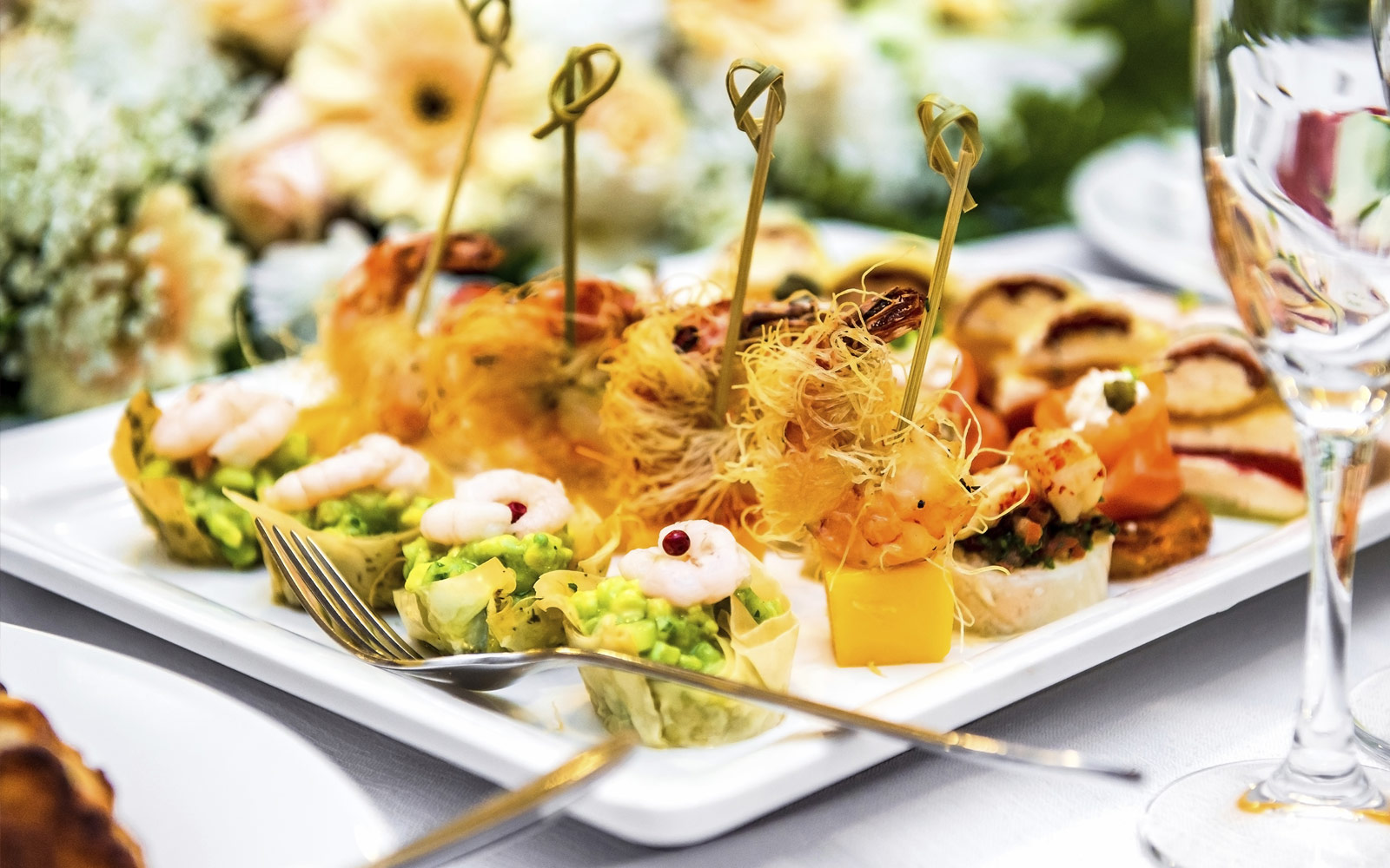 A white plate of assorted appetizers with shrimp and avocado.