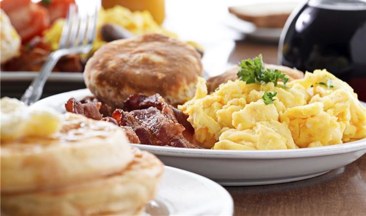 a breakfast plate with scrambled eggs, bacon, and biscuits