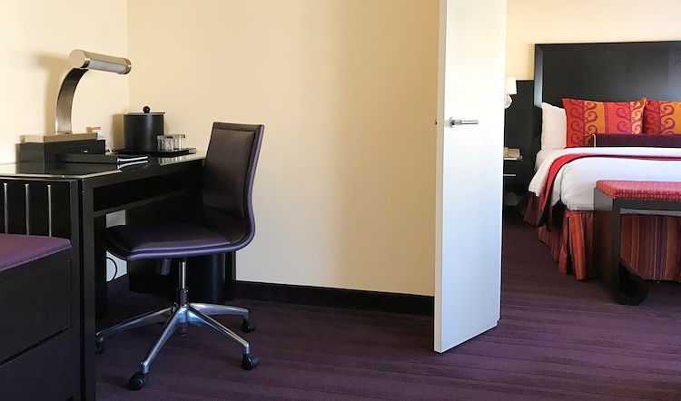 A hotel room with a desk, chair, and bed